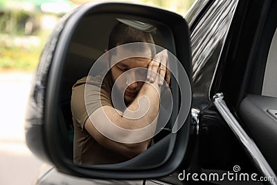 Tired man sleeping on steering wheel in auto, view from car side mirror Stock Photo