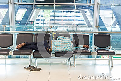 A tired man sleeps on airport seats at Suvarnaphomi International Airport in Bangkok, Thailand Editorial Stock Photo