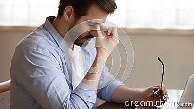 Tired man take off glasses suffering from headache Stock Photo