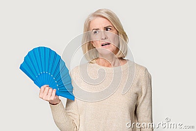 Overheated senior lady cooling herself using waver Stock Photo