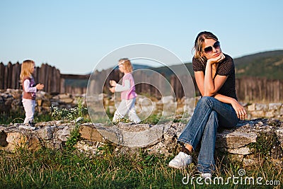 Tired mother sitting on rocks having rest from daily family stress Stock Photo