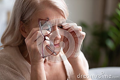 Tired older woman taking off glasses, feeling eye strain Stock Photo