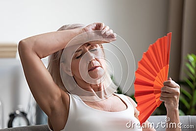 Tired overheated middle aged lady wave fan complain on heat Stock Photo