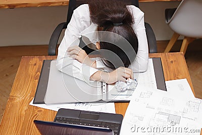 Tired overworked young Asian business woman bend down head on workplace in office. Stock Photo