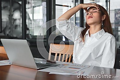 Tired overworked young Asian business woman suffering from severe depression in workplace. Stock Photo