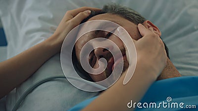 Tired patient lying bed after surgical treatment closeup. Woman hands touch face Stock Photo