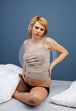 Tired pregnant woman sitting on bed Stock Photo