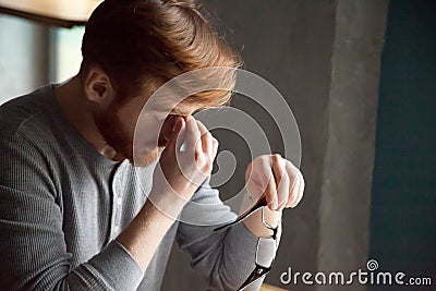 Tired millennial man massaging nose feeling fatigue from work Stock Photo