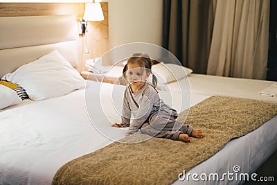 Tired sad toddler kid girl sitting in hotel room on bed Stock Photo