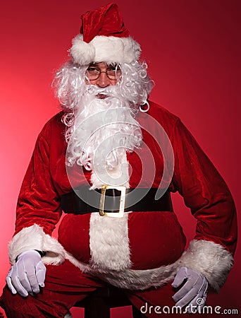 Tired santa claus is resting by sitting on a chair Stock Photo