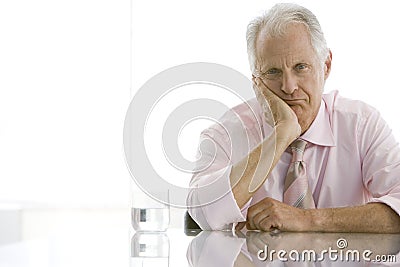 Tired Senior Businessman Sitting At Desk Stock Photo