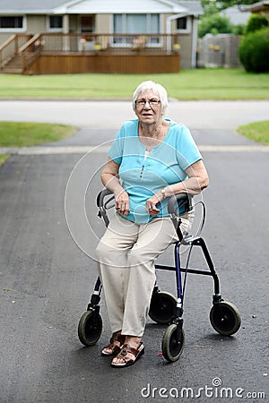 Tired senior woman sitting on walker Stock Photo