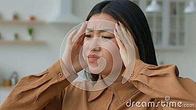 Tired sick Asian woman feel headache pain massaging temples touch aching head hurt grimace suffer from hurt migraine Stock Photo