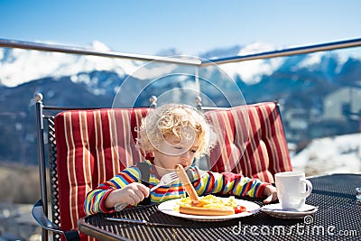 Child eating apres ski lunch. Winter snow fun for kids. Stock Photo