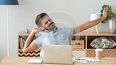 Tired sleepy man stretching, doing easy exercise at workplace Stock Photo