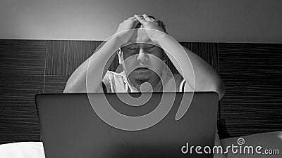 Tired Sleepy Man Working on Laptop untill Midnight on Bed Stock Photo