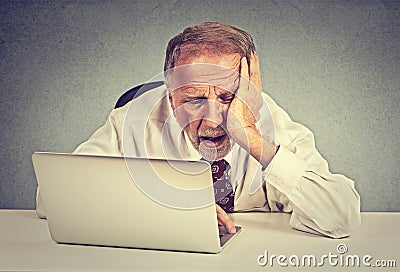 Tired sleepy senior man sitting at his desk in front of laptop computer Stock Photo