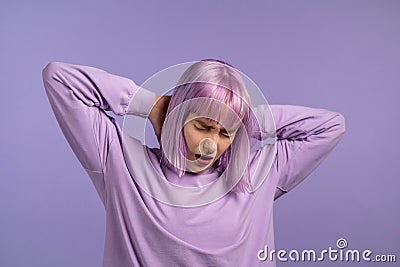 Tired sleepy woman yawns. Girl stretches hands up. Very boring, uninteresting. Violet studio background. Stock Photo