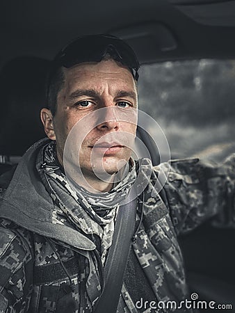 A tired soldier of the Ukrainian army sits in a car and looks into the camera Stock Photo