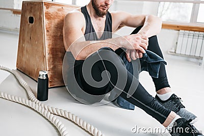 Tired sportsman relaxing on wooden box in fitness gym Stock Photo