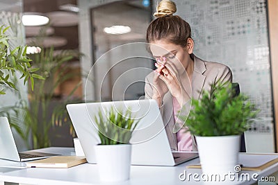 Tired, stressed businesswoman at laptop in office Stock Photo