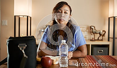 Tired and stressed filipina nurse sitting at home packing lunch for work Stock Photo