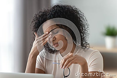 Tired stressed young african woman feel headache or eye strain Stock Photo