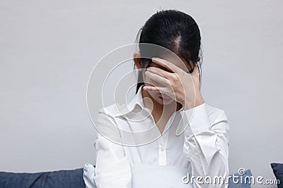 Tired stressed young Asian woman covering face with hands in living room. Stock Photo