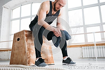Perspiring fit sportsman resting with towel after hard crossfit workout in light hall Stock Photo
