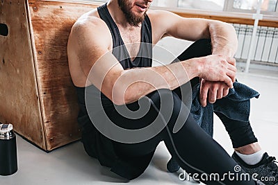 Perspiring fit sportsman resting with towel after hard crossfit workout in light hall Stock Photo