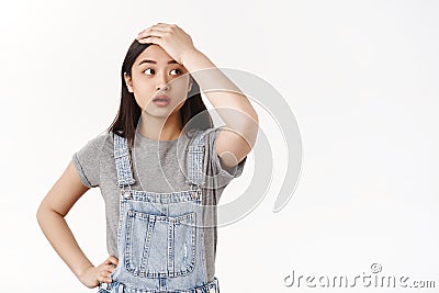 Tired tensed brunette asian girl bothered face troublesome situation touch forehead pressured look aside sighing Stock Photo