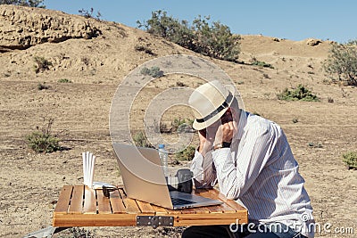 Tired of working on laptop man resting outdoor in mountains, taking a short break Stock Photo