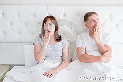Tired yawn middle age couple in bed. Family life and healthy relationships. Health care and morning concept. Copy space Stock Photo