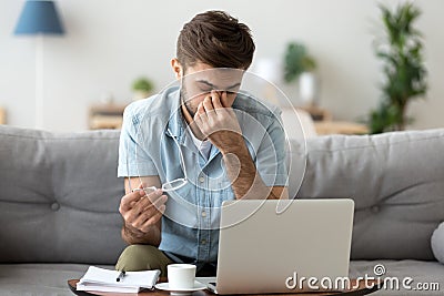 Tired young man feeling eye strain headache after computer work Stock Photo
