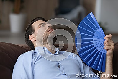 Tired young man wave with hand fan suffer from heatstroke Stock Photo