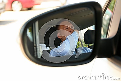 Tired man yawning in his auto, view through car side mirror Stock Photo