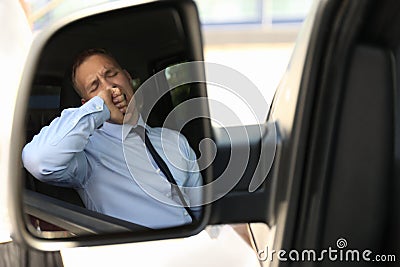 Tired man yawning in his auto, view through car side mirror Stock Photo