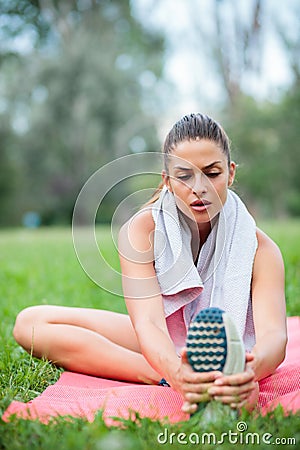 Tired young woman stretching after a workout in a park Stock Photo