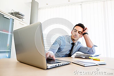 Tiresome businessman works on laptop Stock Photo