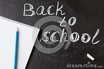Title Back to school written by white chalk and the the notebook with blue pencil on the black school chalkboard Stock Photo