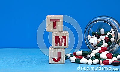 TMJ word on cubes on a blue background with a jar of tablets Stock Photo
