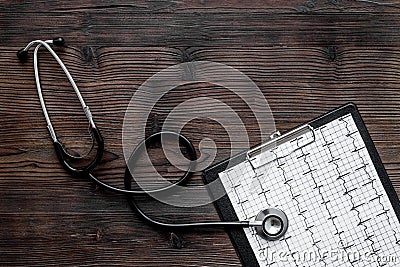 To diagnose heart disease. Cardiogram, stethoscope on dark wooden background top view copyspace Stock Photo