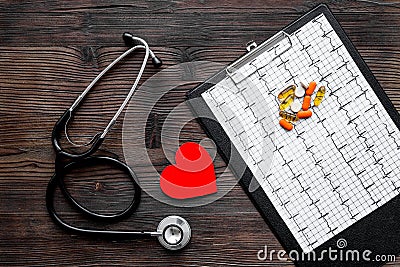 To diagnose heart disease. Heart sign, cardiogram, stethoscope on dark wooden background top view Stock Photo