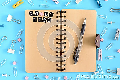 To do list. Open notebook on springs with brownish pages. Stationery scattered in disorder . Stock Photo