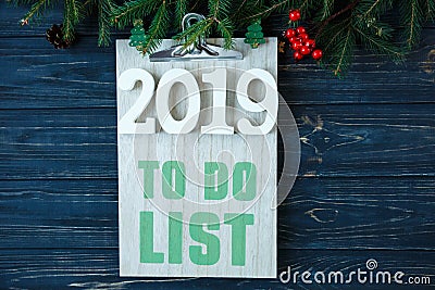 To do list on wooden pad, branches of fir tree, decor on grey wooden table. New Year Goals list, things to do on Stock Photo