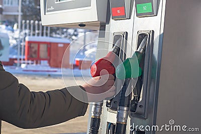 To fill up the car with gasoline at the gas station, a man pours gasoline into the tank of a white car in winter Stock Photo