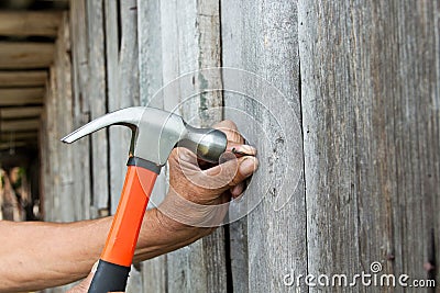 To hammer a nail with a hammer. Older worker carpenter Stock Photo