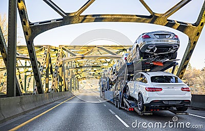 Big rig car hauler carry cars on semi trailer and running on the arched bridge Stock Photo