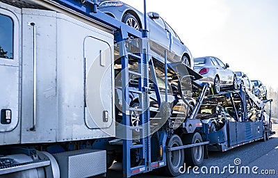 White big rig car hauler long distance semi truck transporting cars on two level semi trailer on the straight road Stock Photo