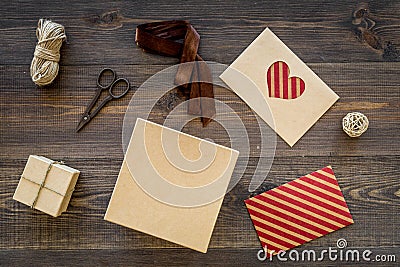 To wrap gift. Box, kraft paper, envelope, greeting card, ribbon, sciccors on wooden background top view Stock Photo